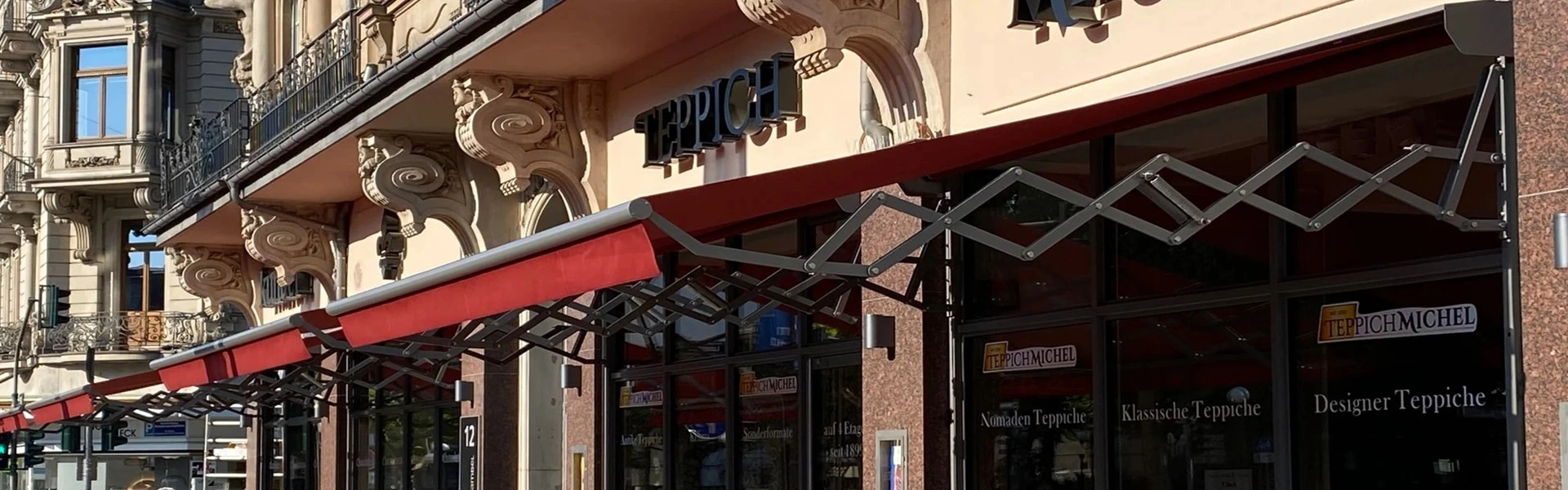 Schaararmscherm bij chocolaterie langs winkelstraat met rood doek