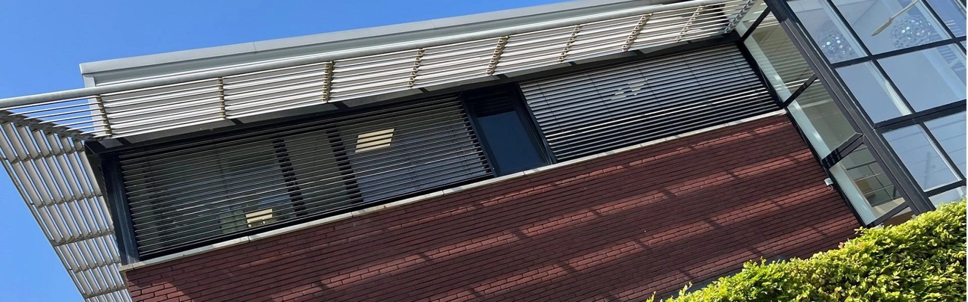 Schuin aanzicht van buitenjaloezieen en glazen gevel bij Nationale Fietsprojecten