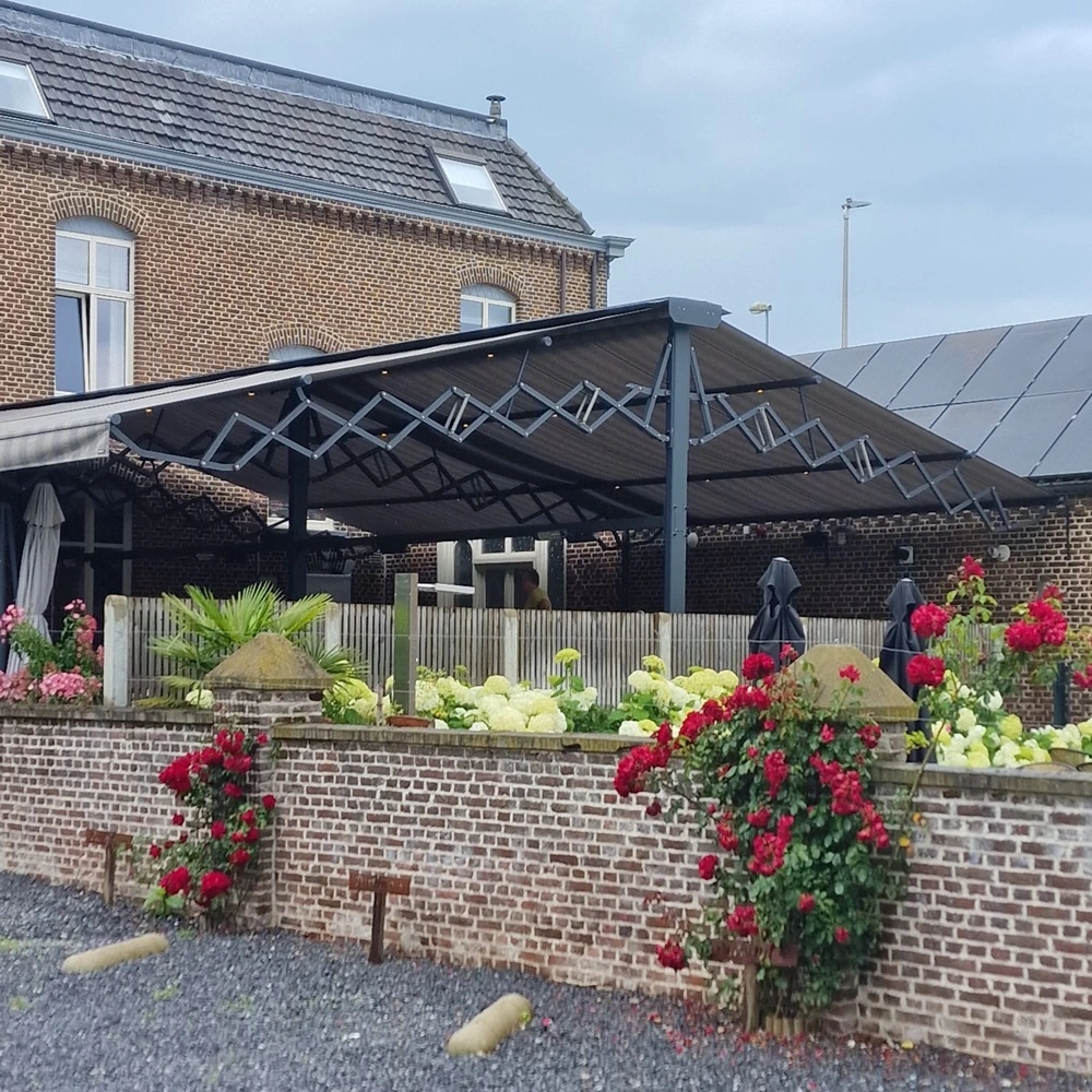 Vrijstaand schaararmscherm Vertigo over terras met bloemen en bakstenen muur