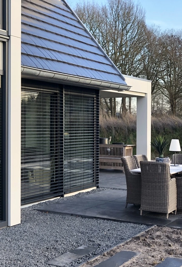 Zijaanzicht van buitenjaloezie en houten gevel bij woning in Joure