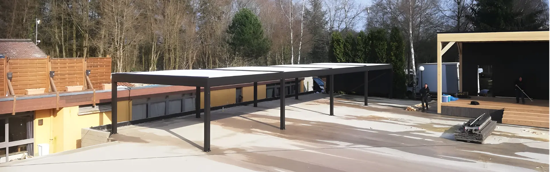 Zwarte overkapping op campingterrein met open dak en bosrijke achtergrond