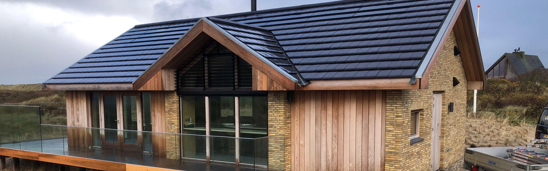 Achterzijde woning met louvre zonwering en glazen balustrade