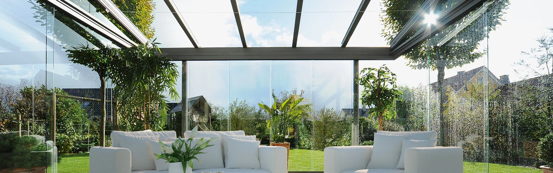 Gezellige zithoek in een glazen tuinkamer met uitzicht op een groene tuin