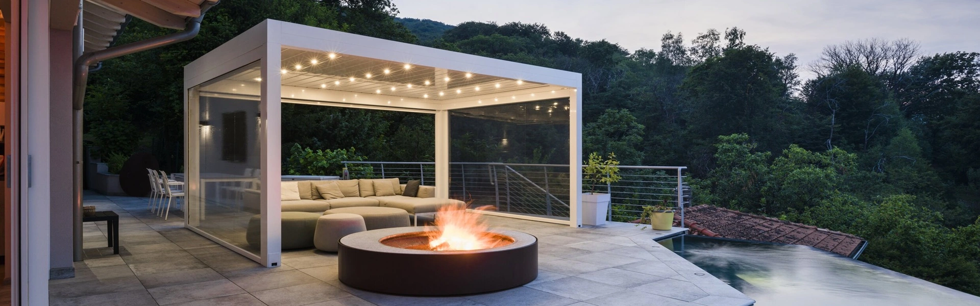 Lamellen overkapping Joy met sfeerverlichting en lounge bij vuurplaats