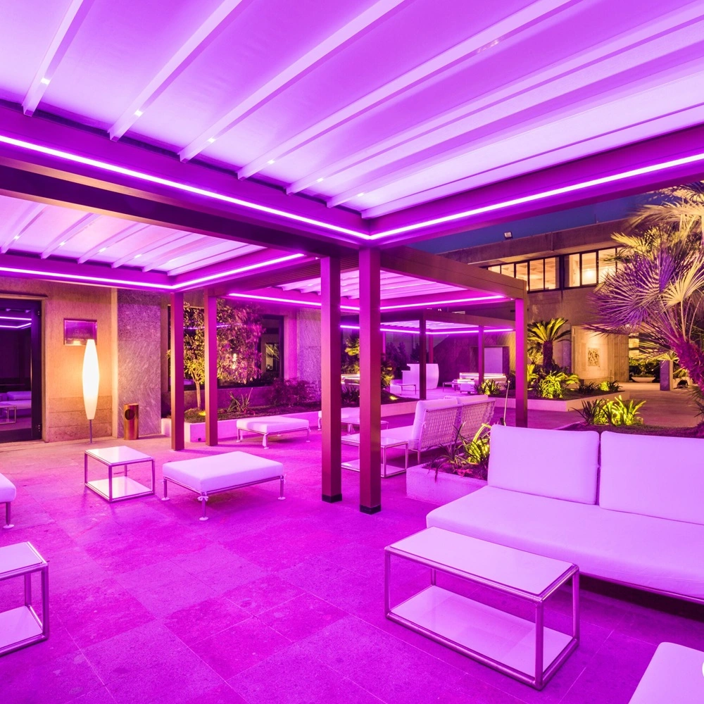 Loungegedeelte onder ledverlichte pergola met paarse sfeerverlichting