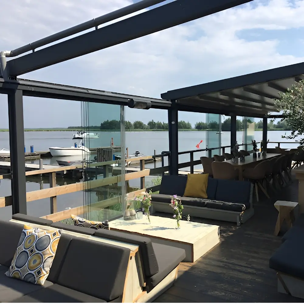 Overdekt terras met glazen schuifwanden en uitzicht op een meer