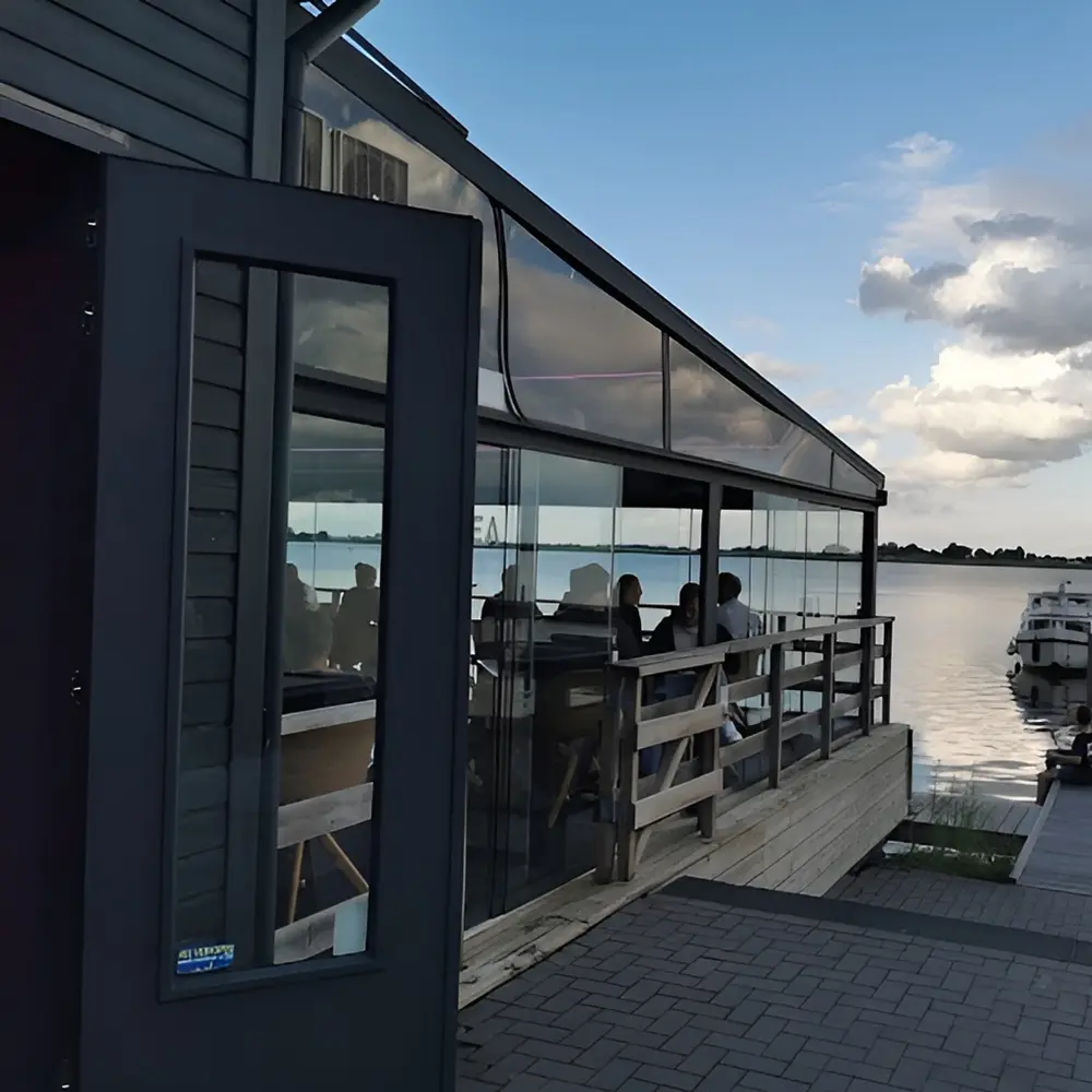 Restaurantterras met glazenschuifwanden en uitzicht op de haven