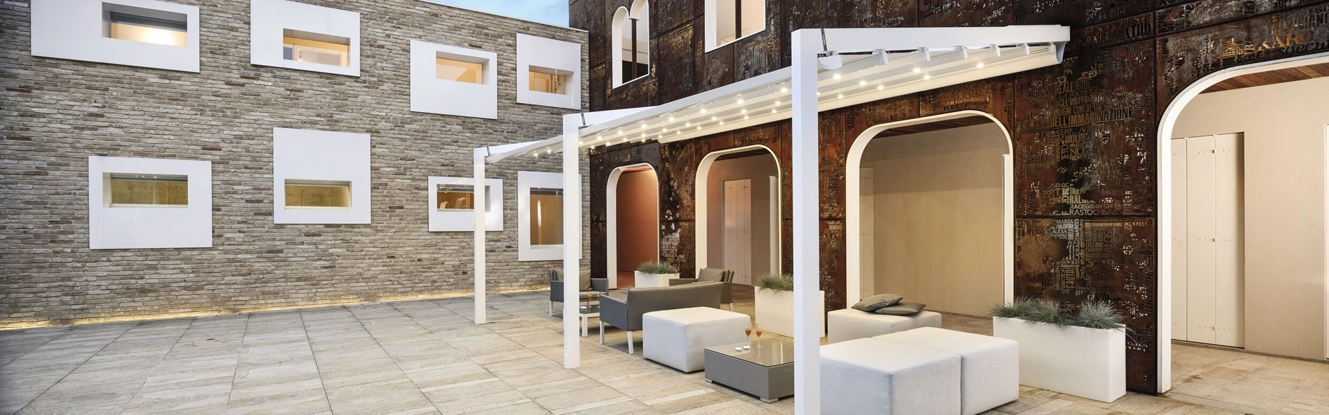 Schuine overkapping Luce met sfeerverlichting boven een modern terras in een binnenplaats