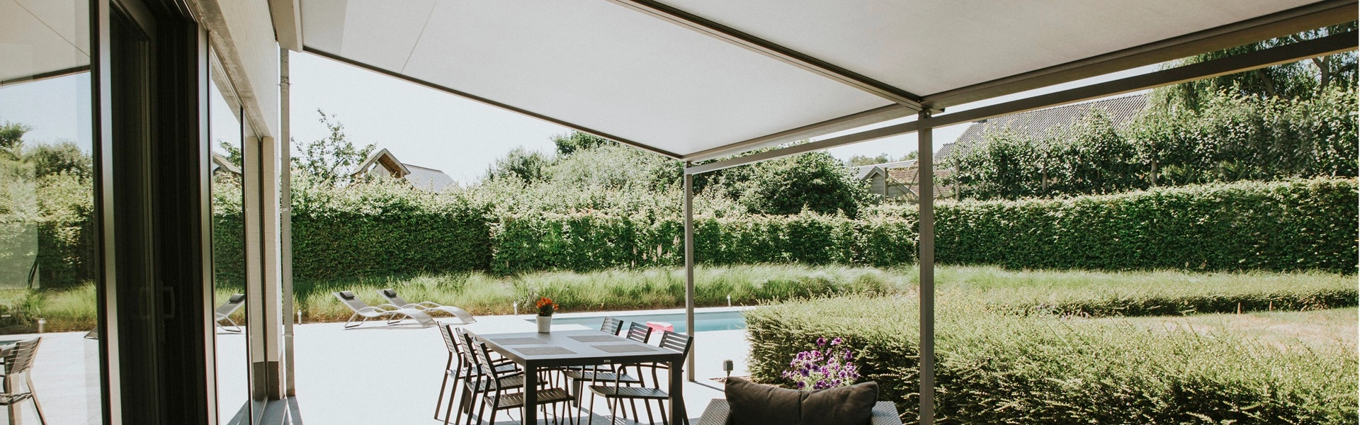 Uitzicht vanaf een overkapping met doek Versuz op een terras met zwembad