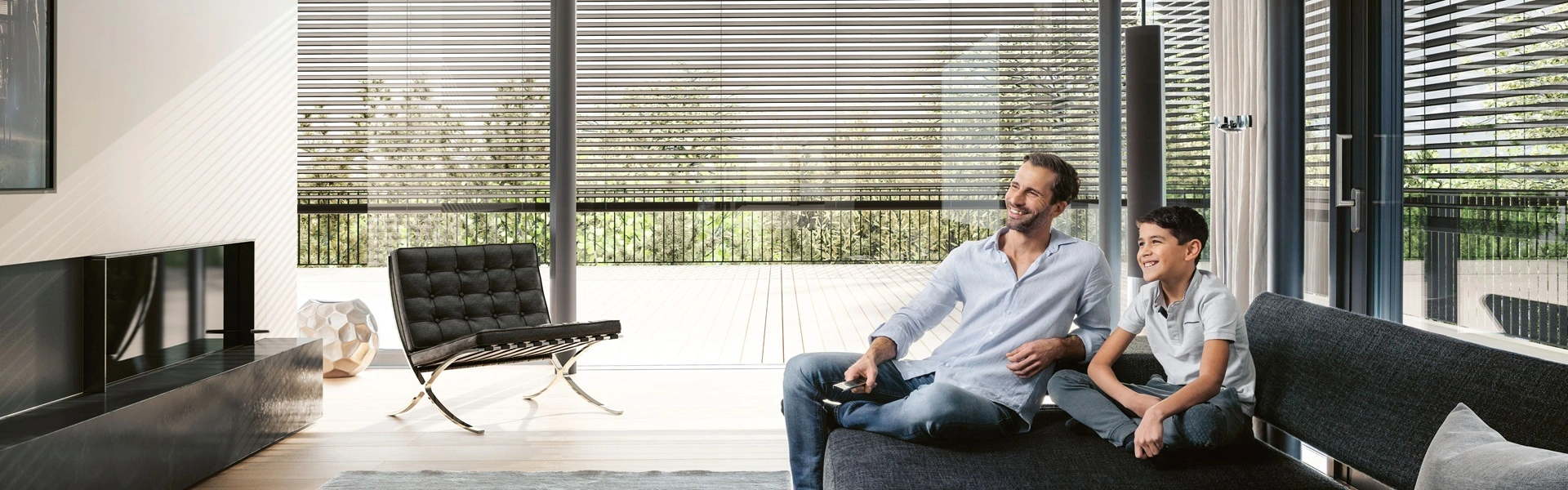 Vader en zoon ontspannen met domotica-raffstore in lichte woonkamer