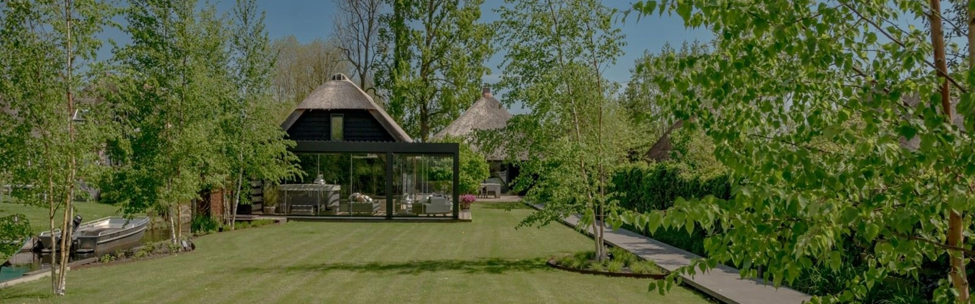 Vrijstaande glazenschuifwanden bij een villa met rieten dak