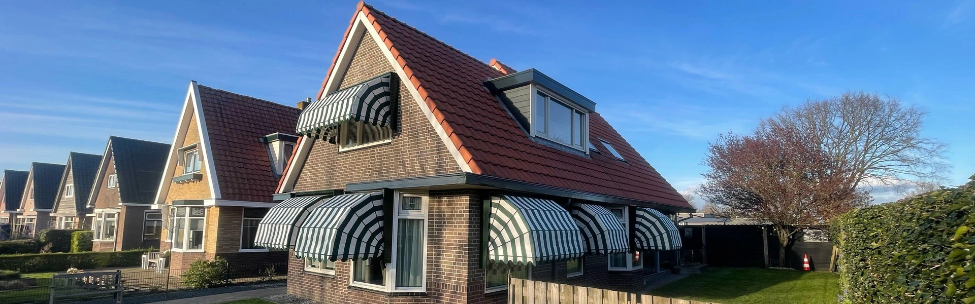 Vrijstaande woning met houten markiezen in een groene tuin en een schutting