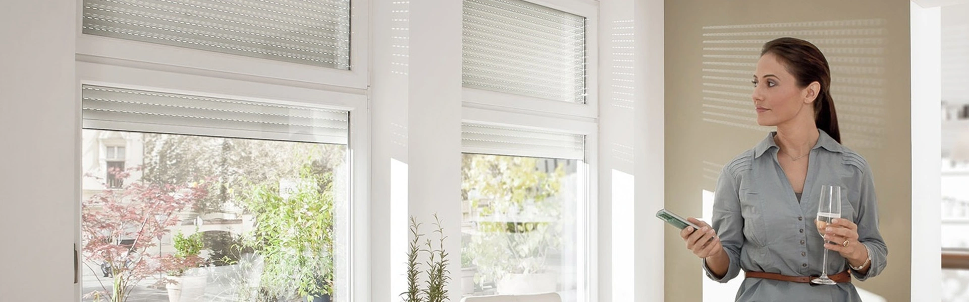 Vrouw bedient elektrische rolluiken met Somfy-app in lichte woonkamer