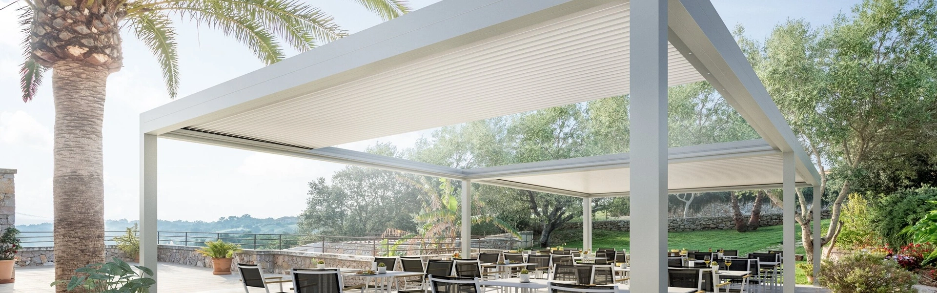 Witte tuinkamer met lamellen Sway op een terras omgeven door palmbomen