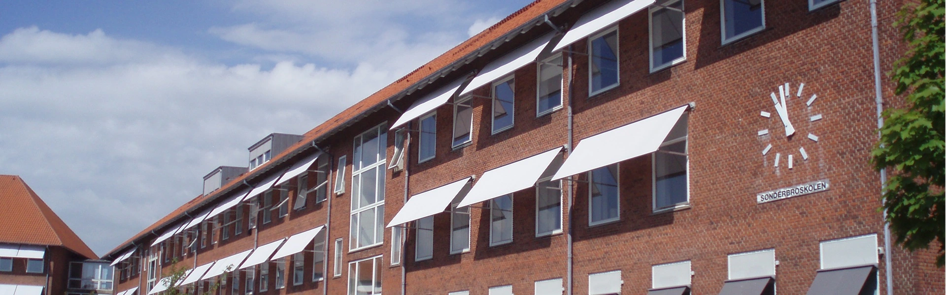 Witte uitvalschermen aan de gevel van een rood bakstenen gebouw