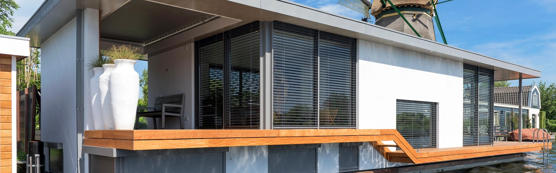 Woonboot met buitenjaloezieen, wit geveldesign en wateromgeving