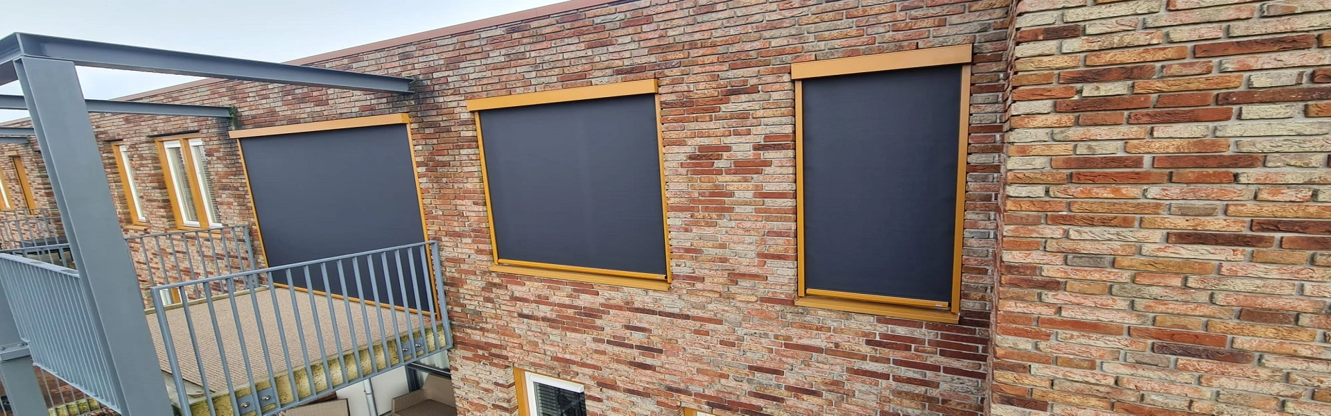 Zipscreens met goudkleurige omlijsting op gevel