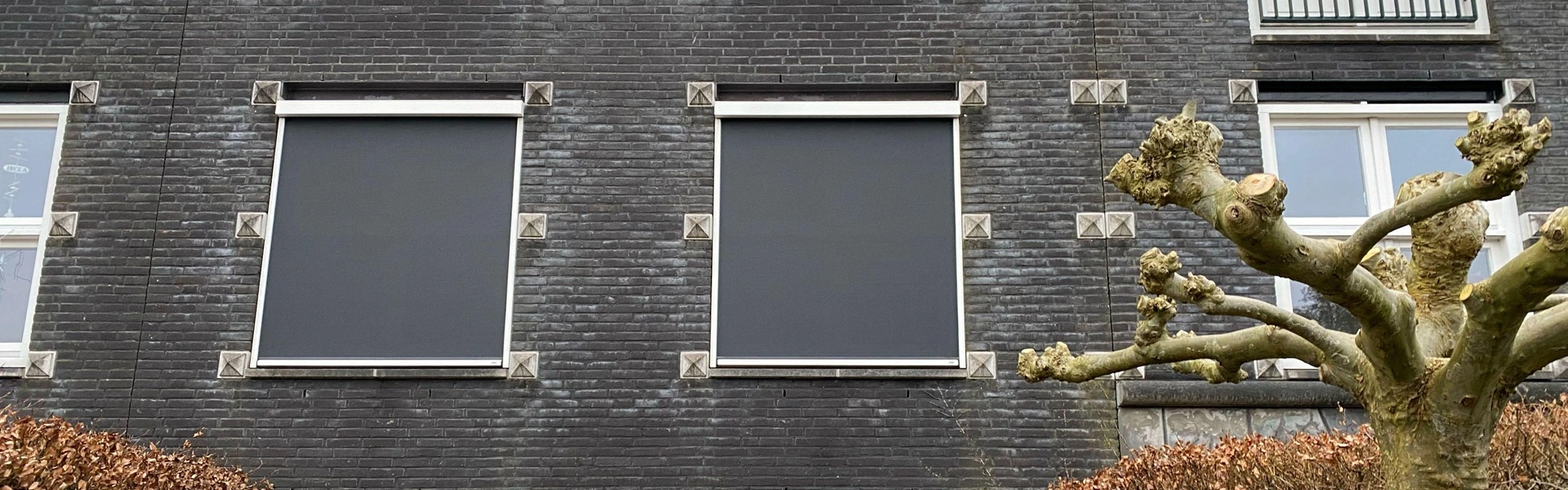 Zipscreens op zwarte bakstenen gevel met tuin