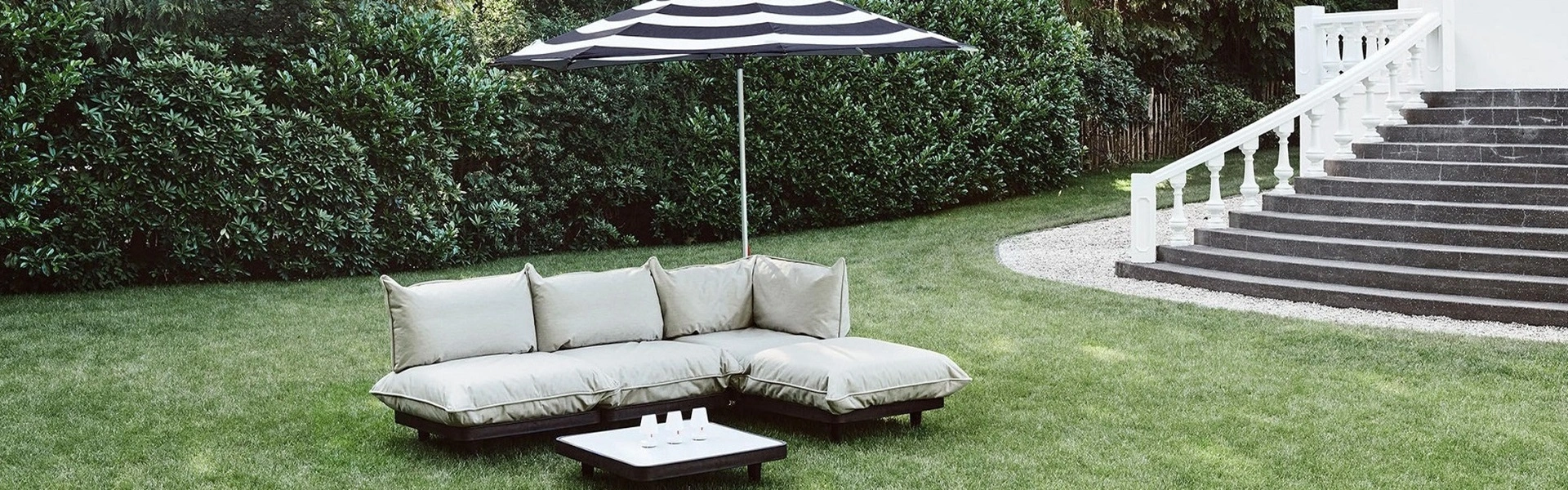 Zwarte en witte lounge bank met parasol op groene grasmat