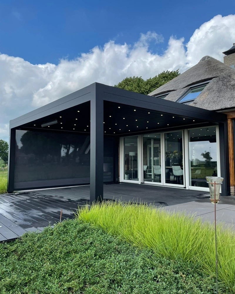 Zwarte lamellen overkapping Varia met LED-verlichting aan een rieten woning Zwarte lamellen overkapping Varia met LED-verlichting aan een rieten woning