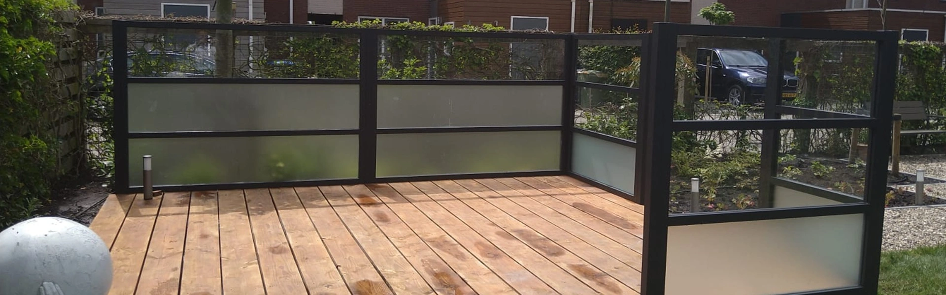 Glazen windscherm op houten terras in Leeuwarden door Veldman Zonwering