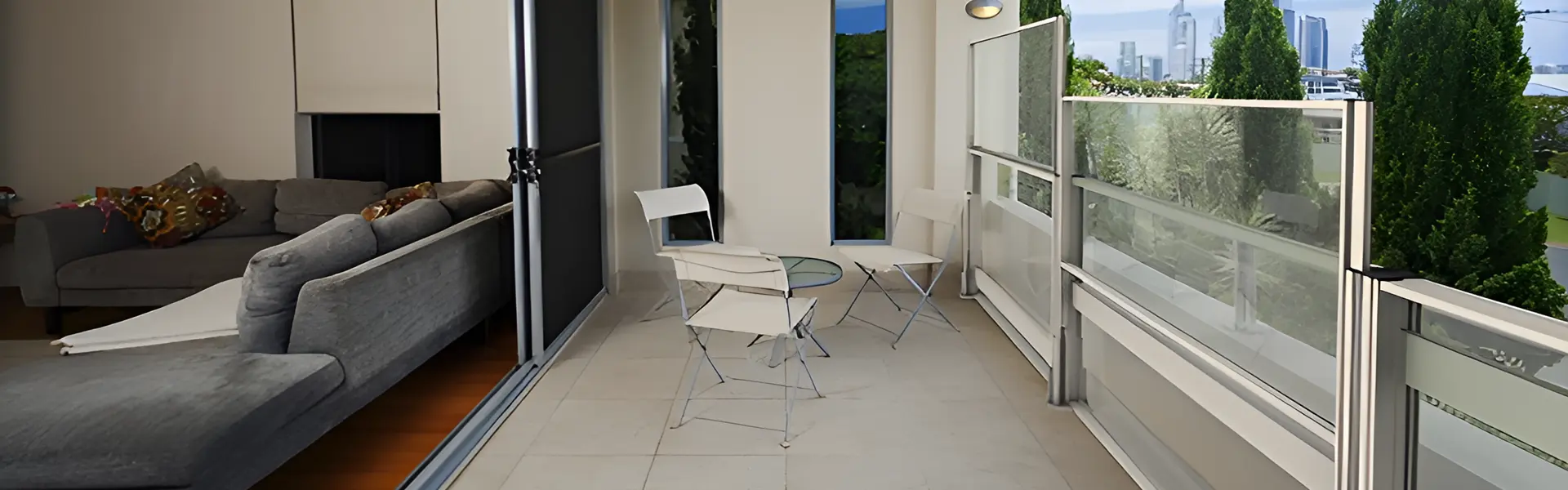 Glazen windschermen op balkon met uitzicht op groene omgeving en stad