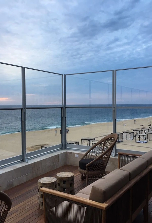 Glazen windschermen op terras in Griekenland met uitzicht op zee en strand