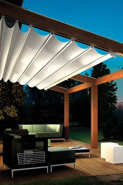 Houten overkapping met verlicht schuifdak en loungehoek in de avond Houten overkapping met verlicht schuifdak en loungehoek in de avond