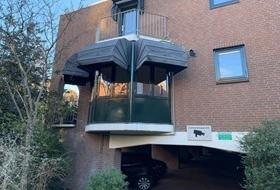 Markiezen met donkere stof op een balkon aan een appartementencomplex
