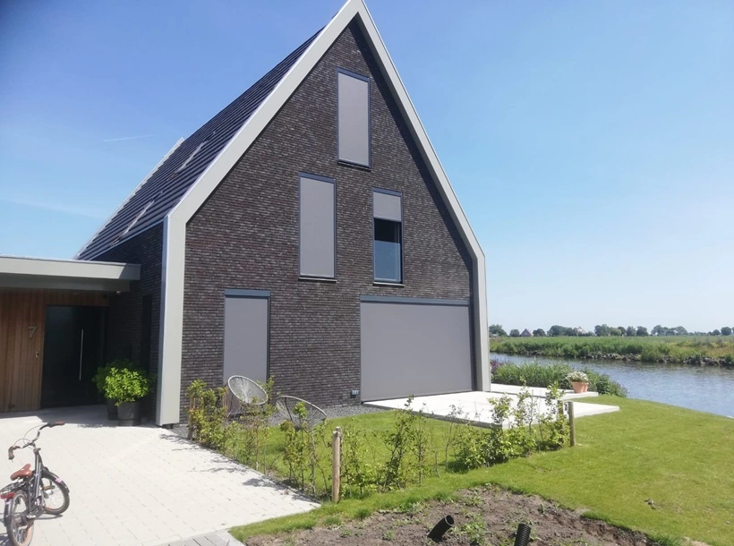 Screens op zwarte gevel van moderne woning aan het water