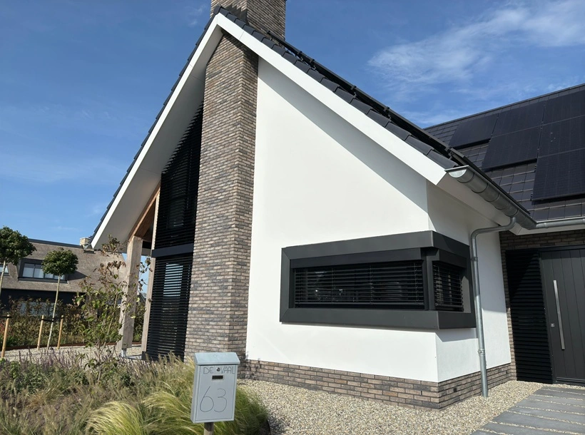 Woning met buitenjaloezieen, witte gevel en donkere bakstenen accenten