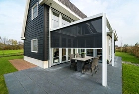 Zwarte screens op terrasoverkapping bij een moderne woning