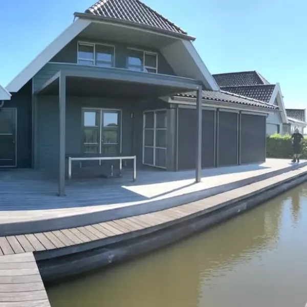 huis aan het water met een terrasoverkapping met doek