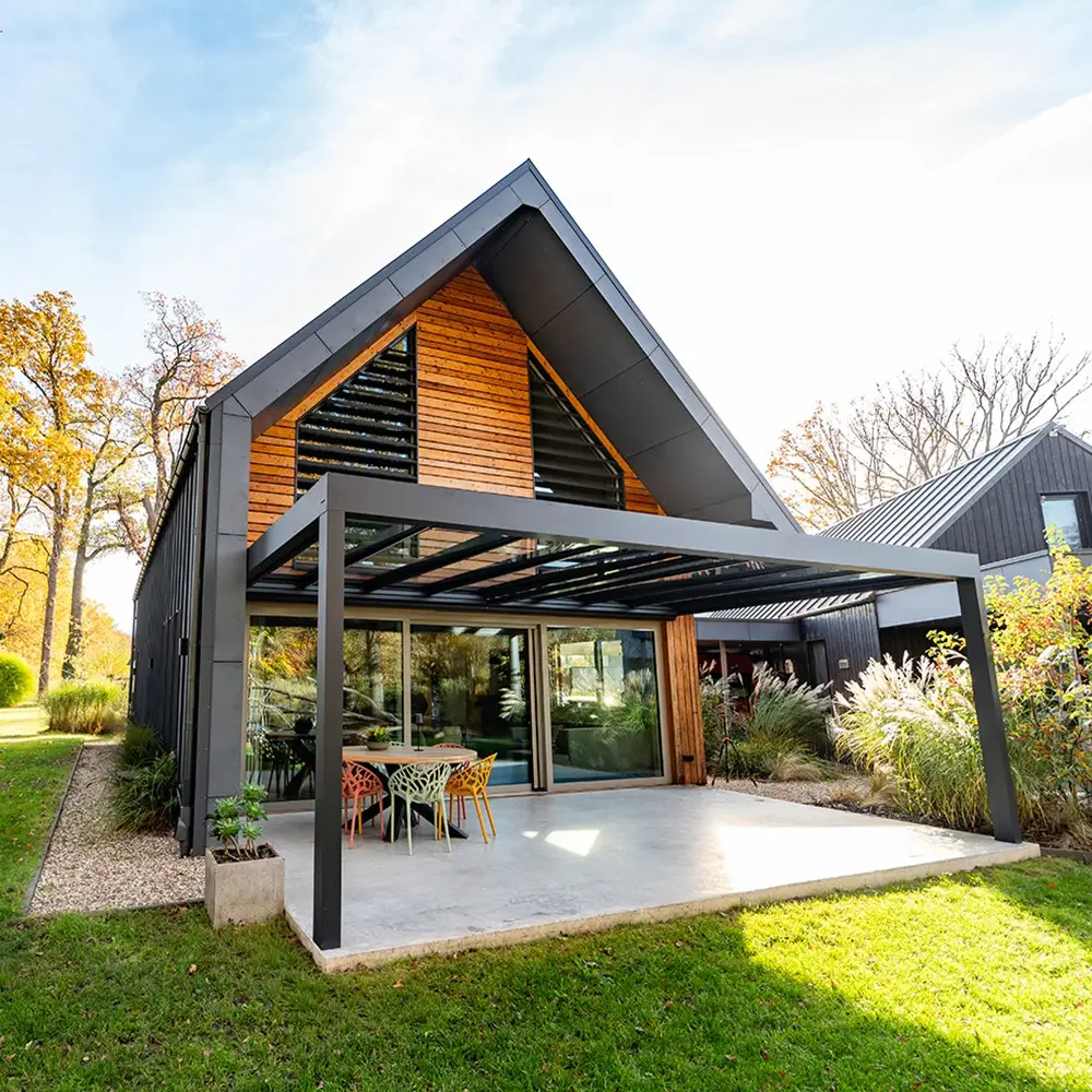 glazen terrasoverkapping antraciet aan woning met houten gevel en herfsttuin