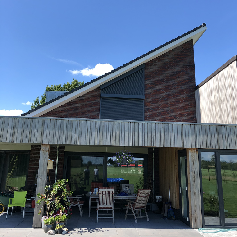 Rolluik op schuine gevel van woning met overkapping en tuinmeubilair